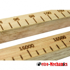 Close-up of two wooden measuring sticks marked with numerical values and black lines; the numbers 16000 and 16500 are visible on one stick. The Petro-Mechanics logo appears in the bottom right corner.